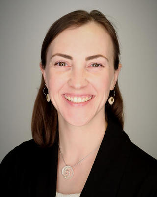 A headshot of a smiling white woman with brown hair.