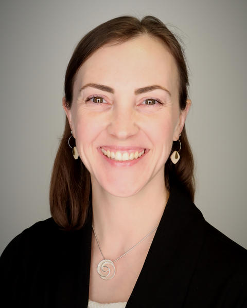 A professional headshot of a brunette white woman wearing a black blazer and white blouse.