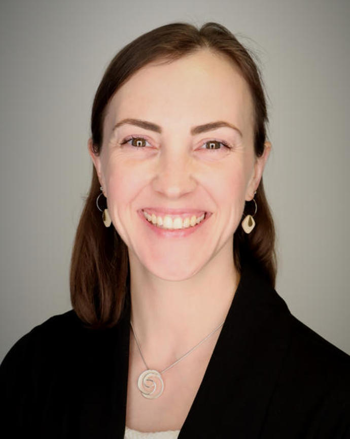 A headshot of a smiling white woman with brown hair.